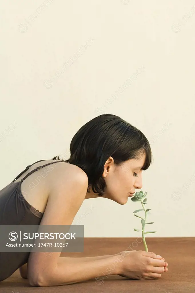 Woman smelling sedum plant, eyes closed, side view