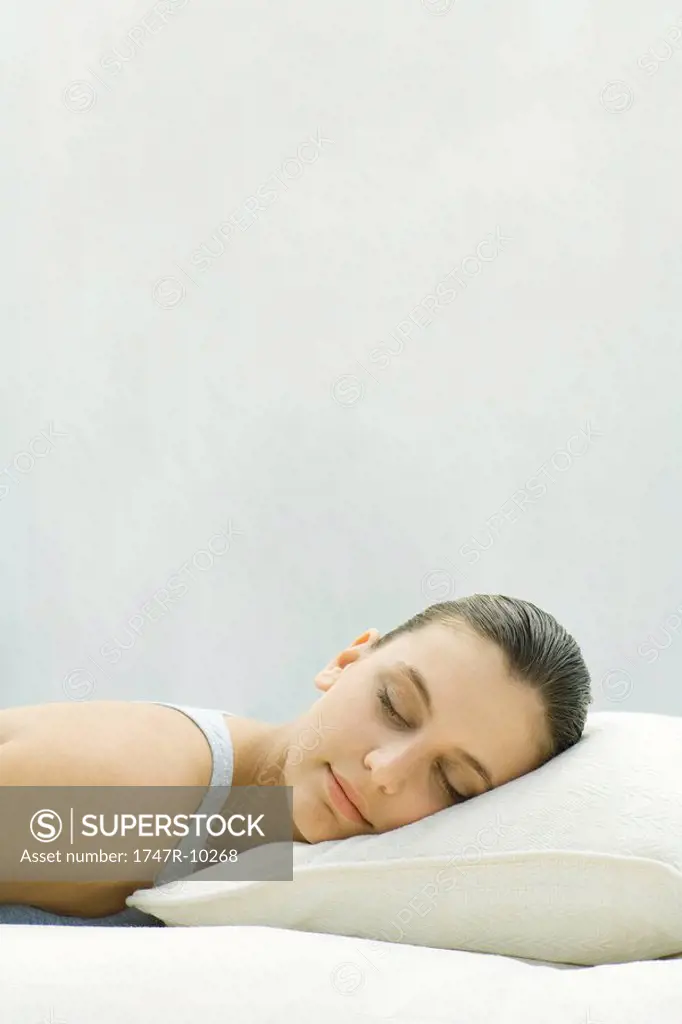 Woman resting head on pillow, eyes closed