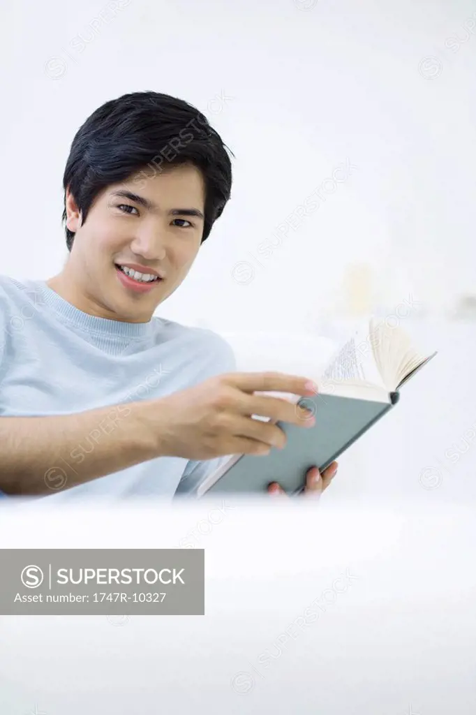 Man smiling at camera, holding book