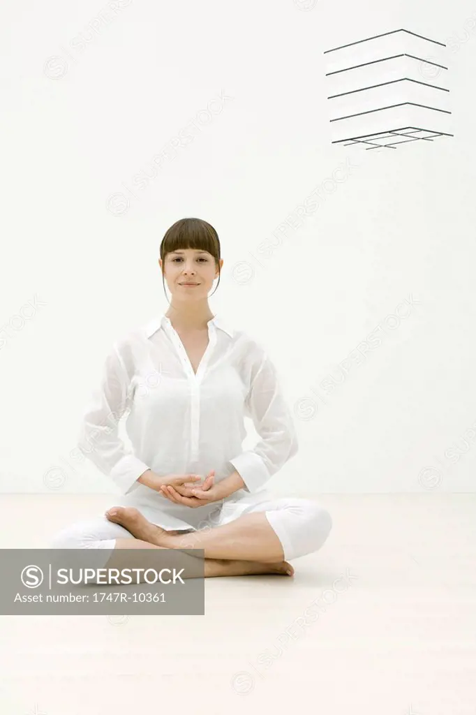Woman sitting in meditative position, smiling at camera