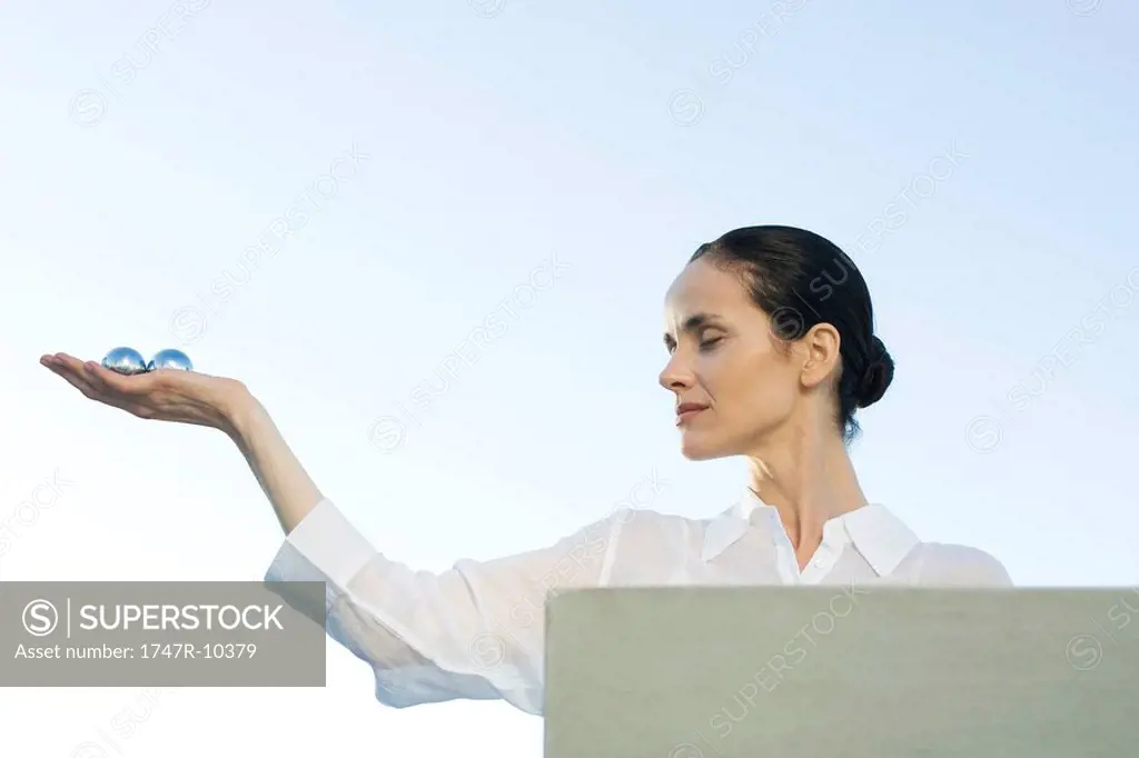 Woman holding out yin yang balls in palm of hand