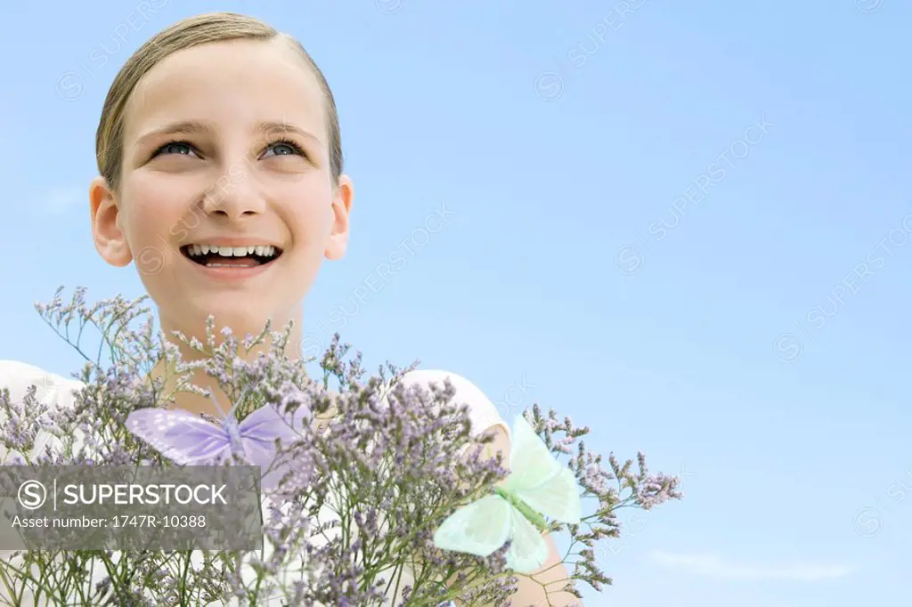 Girl with plant and fake butterflies, looking up, smiling