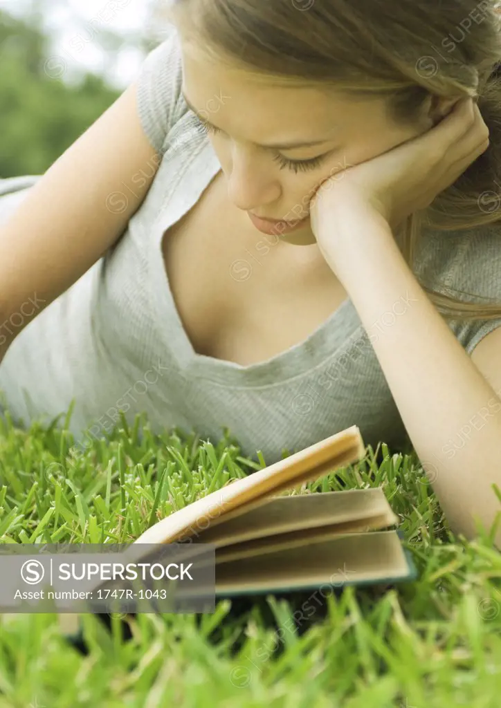 Young woman reclining in grass with book
