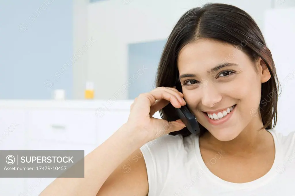 Woman using cell phone, smiling at camera
