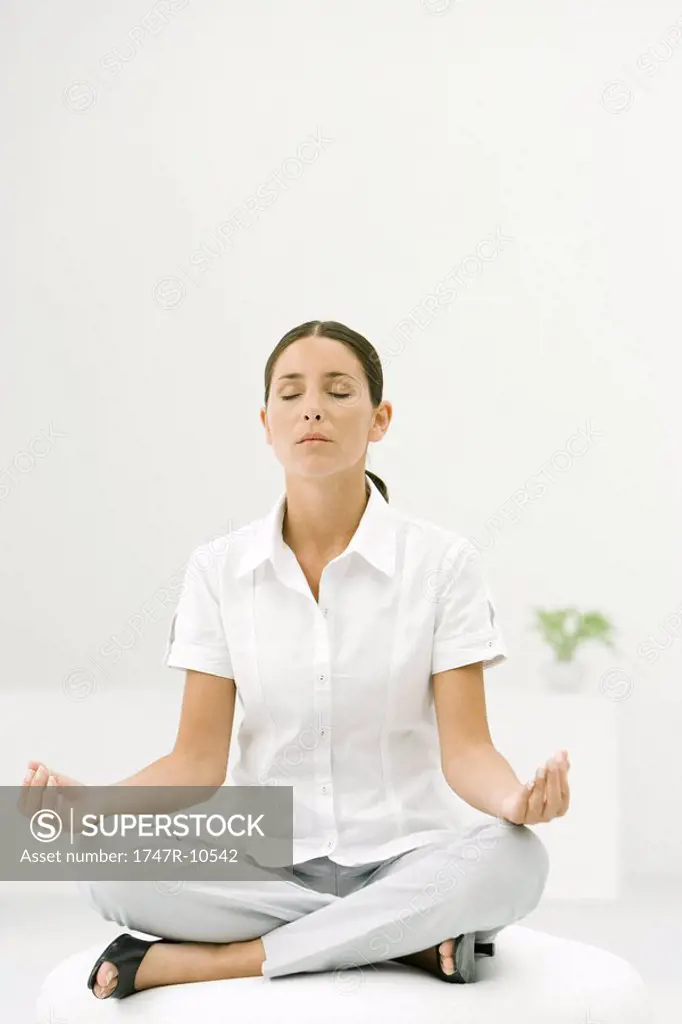 Woman sitting cross-legged, meditating with eyes closed