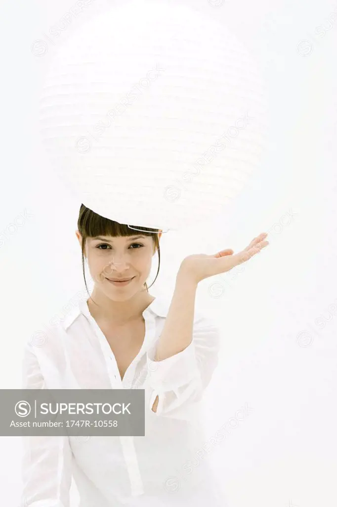 Woman looking underneath paper lantern, smiling at camera