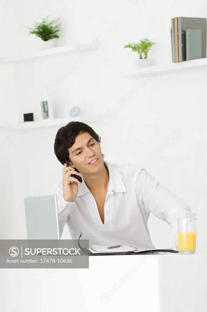 Man sitting, using cell phone, looking away, smiling