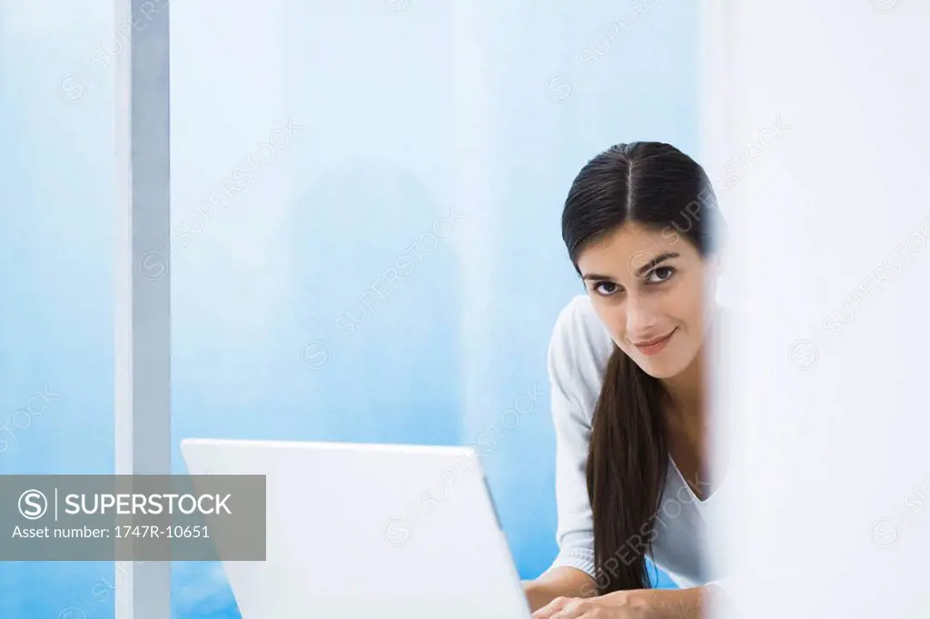 Woman with laptop, smiling at camera, cropped view