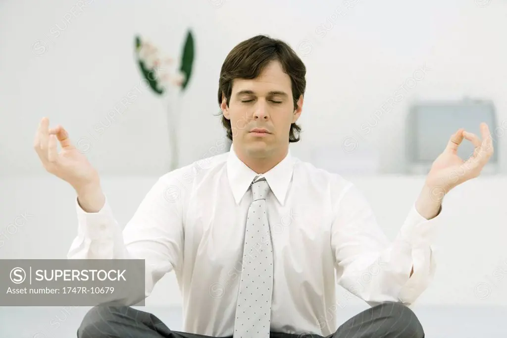 Businessman sitting in lotus position, eyes closed