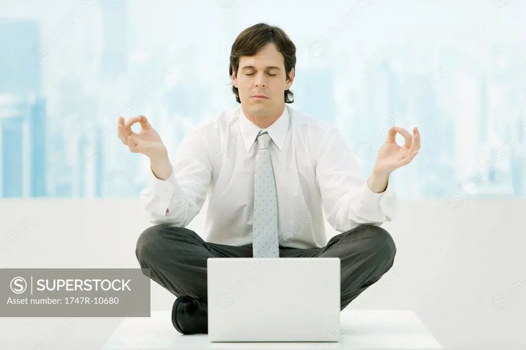 Businessman meditating in office, eyes closed