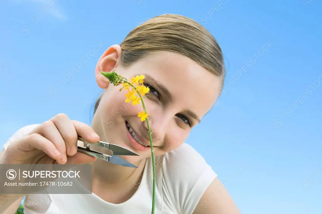 Girl pretending that she is going to cut a long stemmed flower