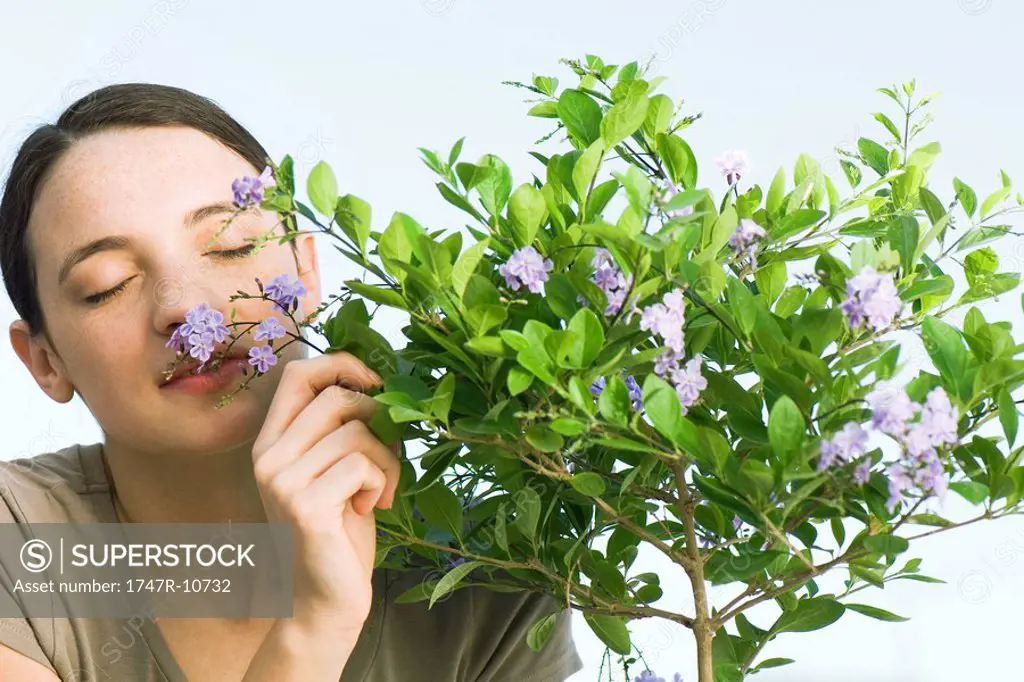 Young woman smelling flowering plant