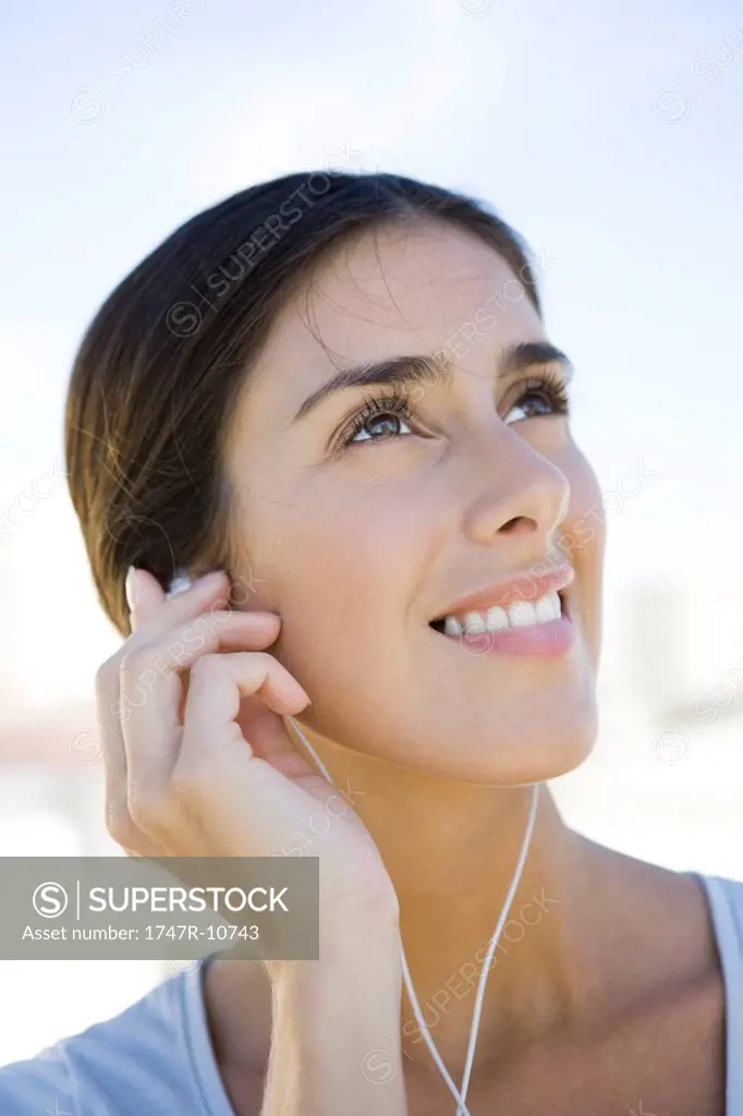 Woman looking up, listening to earphones