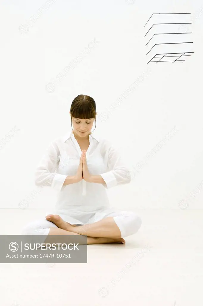 Woman meditating, sitting cross-legged, hands together, eyes closed