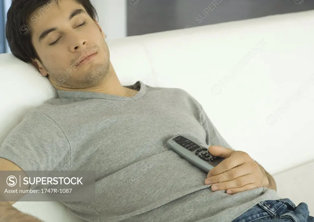 Man sleeping on sofa with remote control on chest