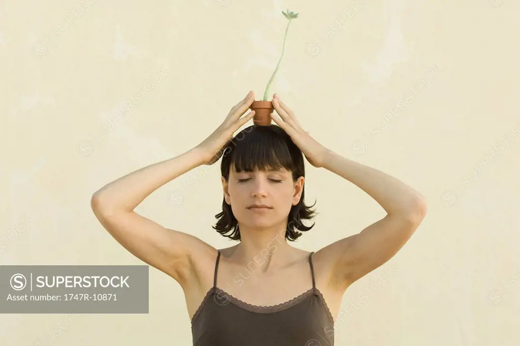 Woman balancing small potted plant on her head