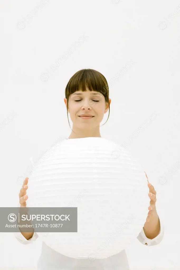 Woman holding large sphere, eyes closed