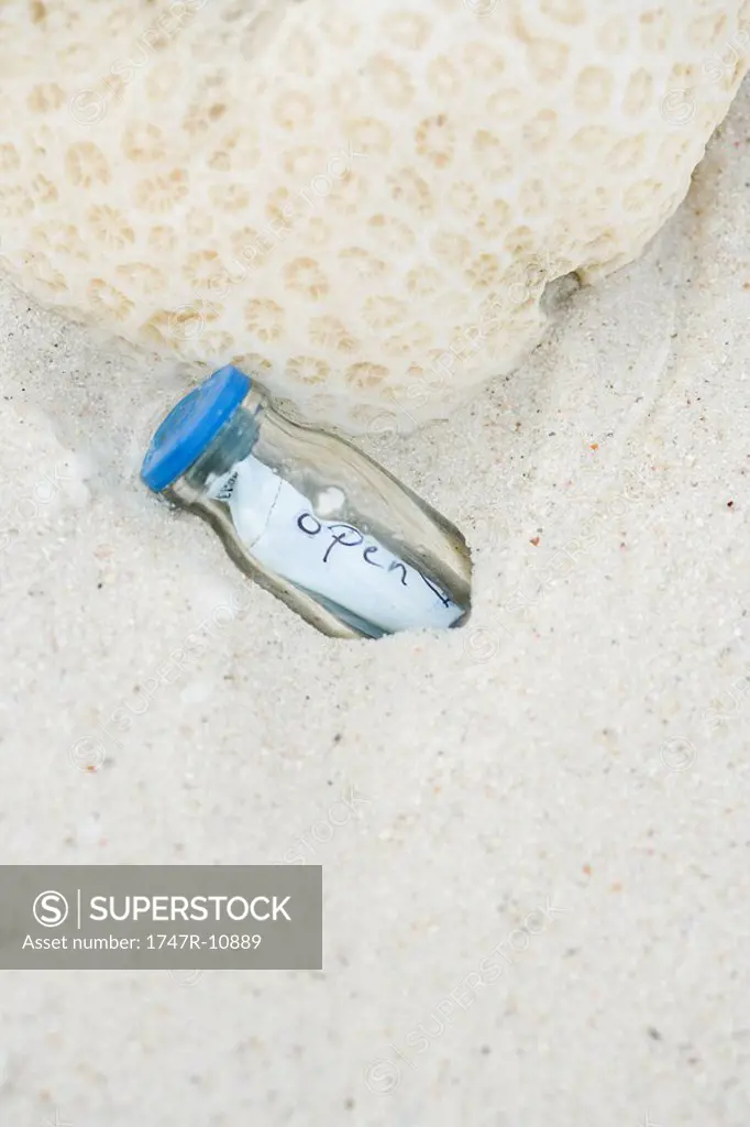 Message in a bottle, partially buried in sand