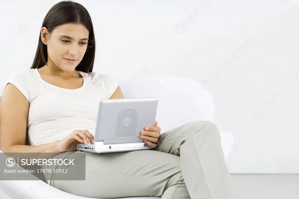 Woman watching portable DVD player, sitting in chair