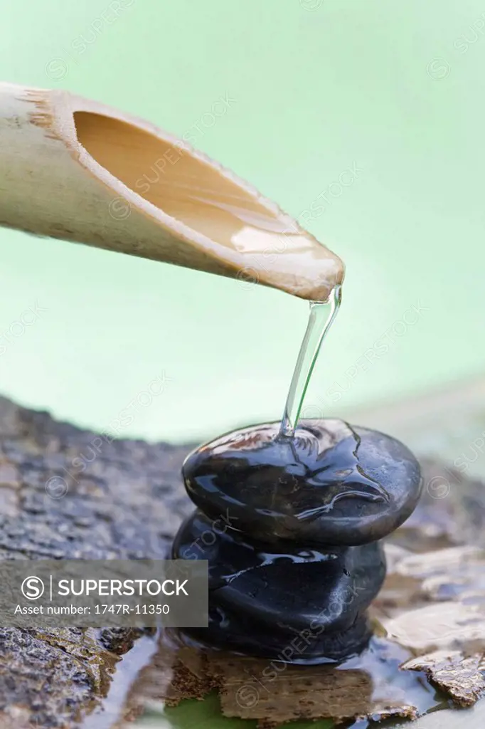 Wooden spout pouring water over stack of stones