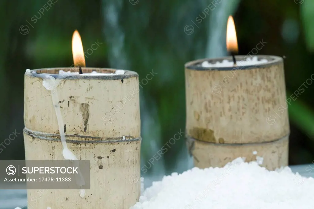 Lit candles in bamboo holders surrounded by snow