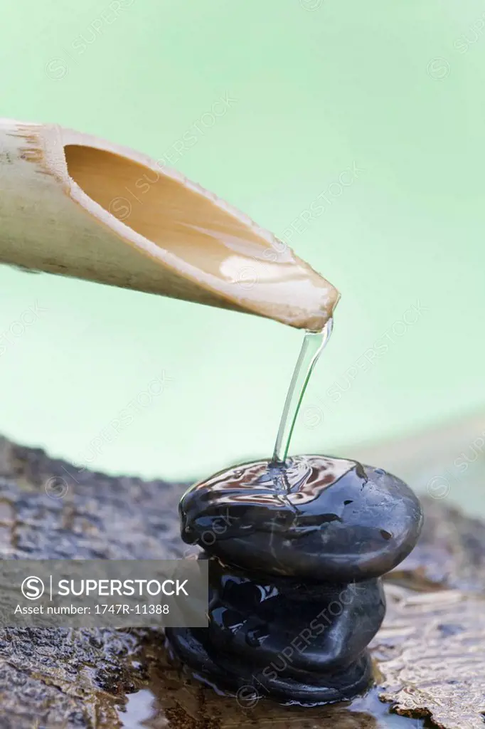 Bamboo spout pouring water on stack of stones