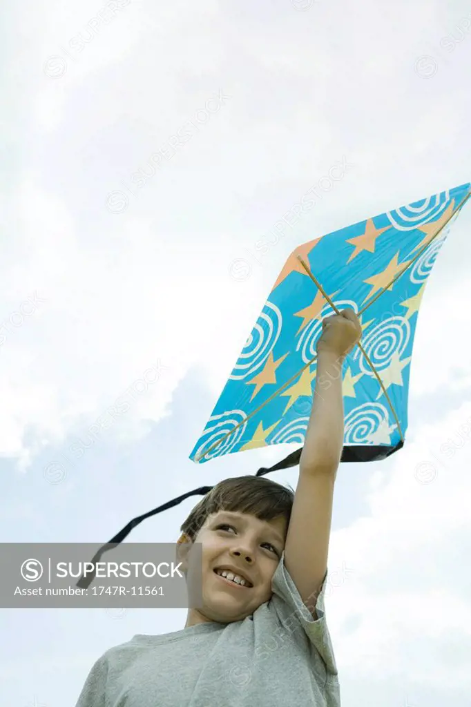 Boy holding kite above head, low angle view