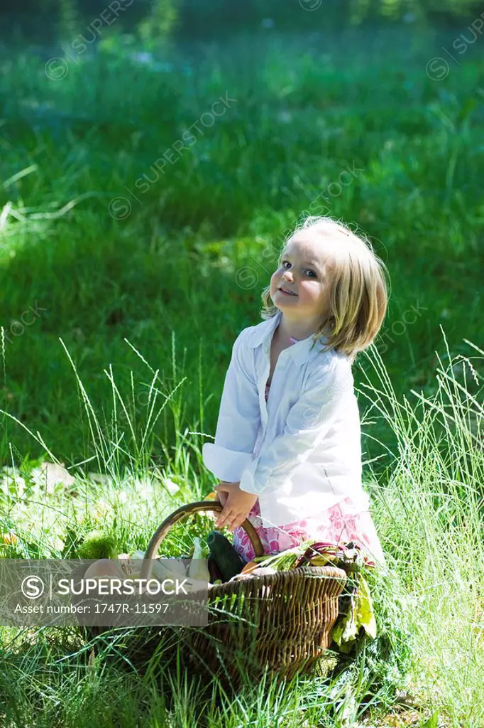 Little girl holding large basket full of fresh produce