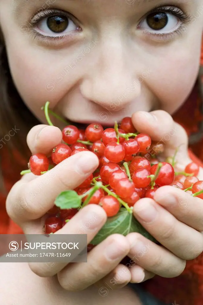 Teenage girl holding up large handful of red currants, close-up
