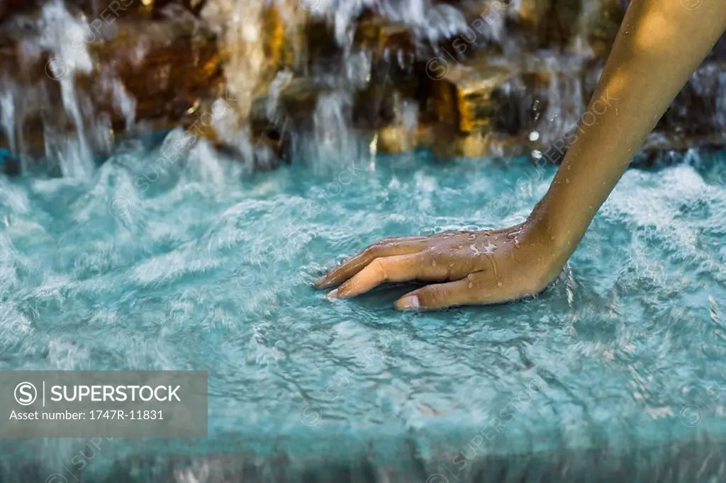 Water flowing from waterfall over woman´s hand