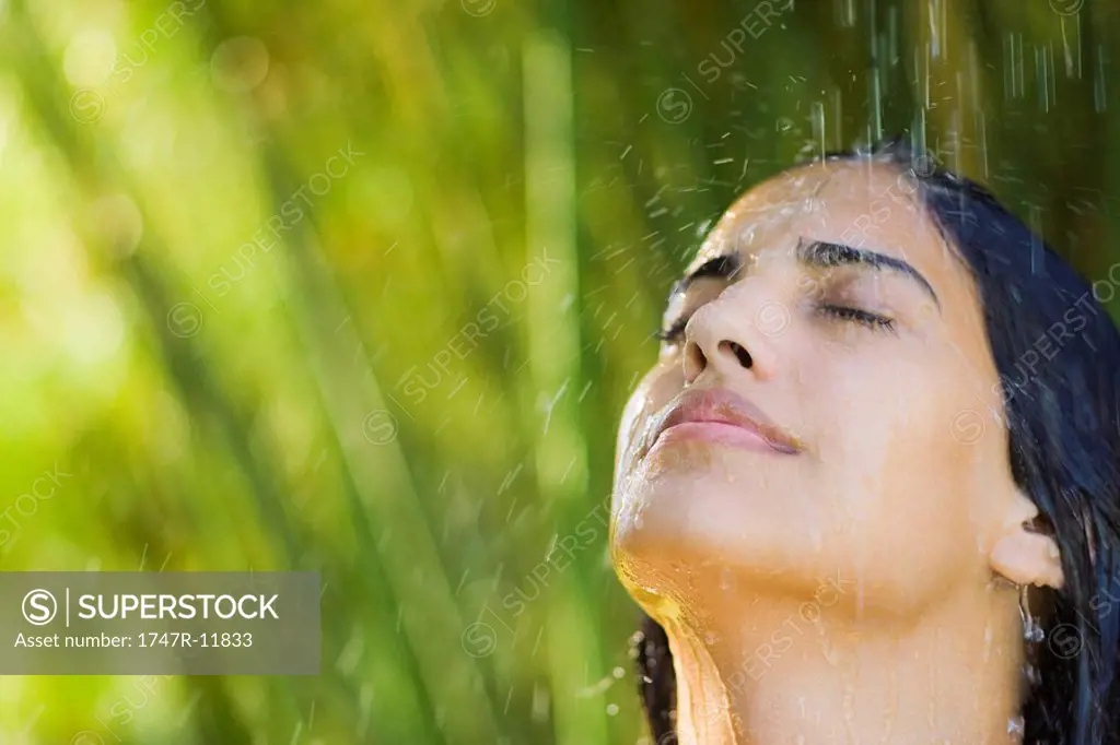Young woman under falling water, portrait