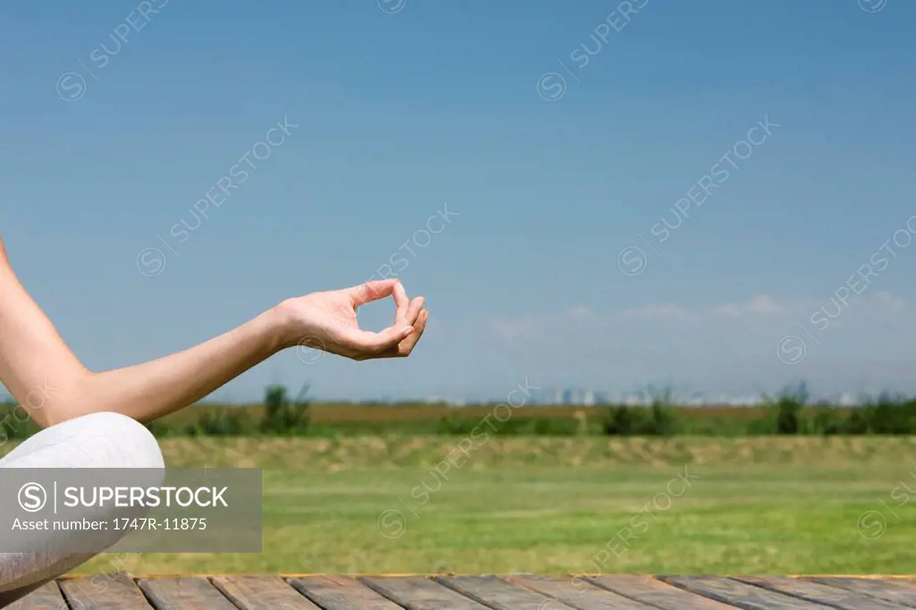 Woman meditating outdoors, cropped view