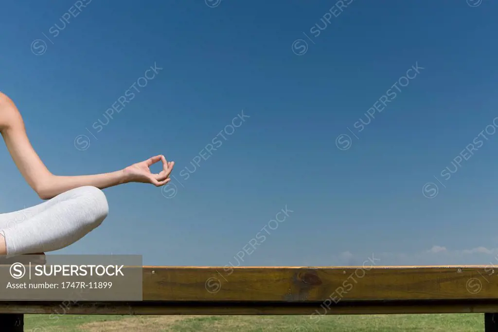 Woman meditating in lotus position outdoors, cropped