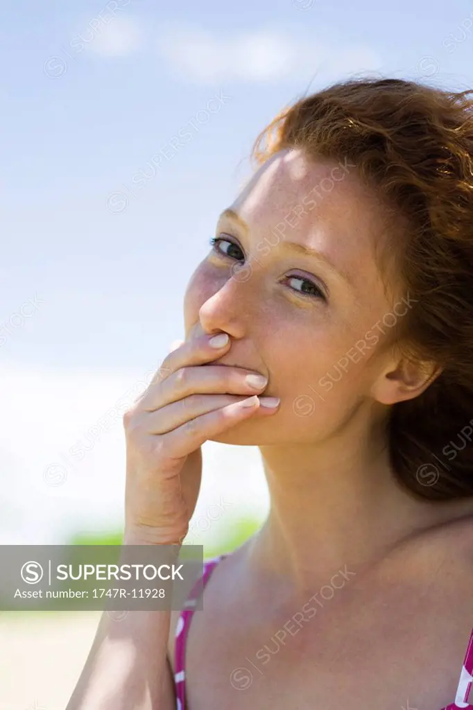 Young woman covering mouth with hand, portrait