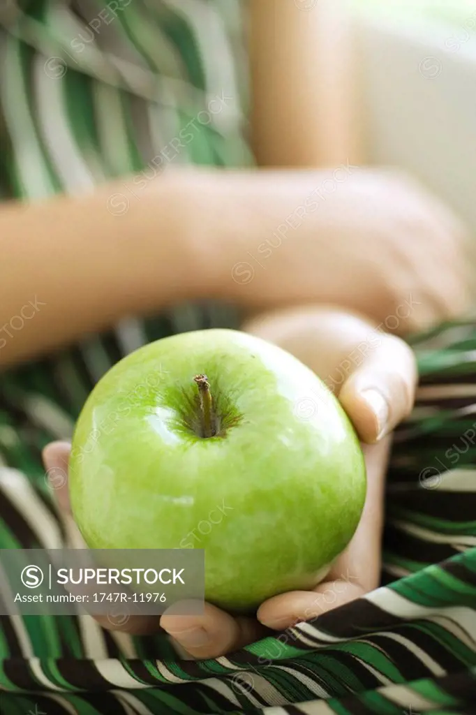 Woman holding green apple, cropped
