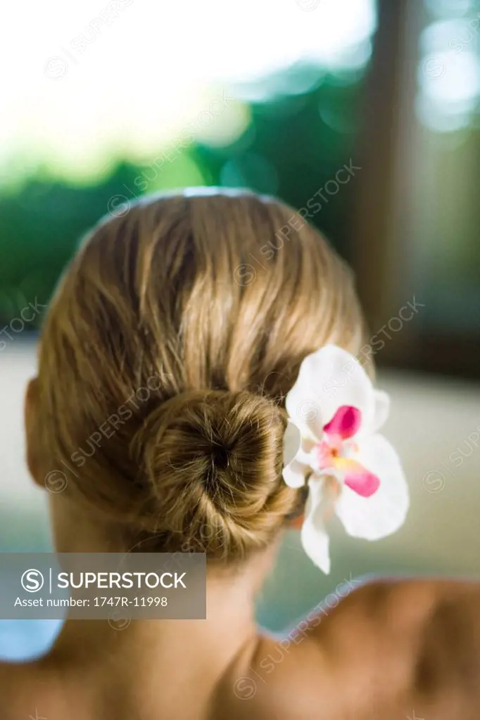 Woman with orchid in hair, rear view