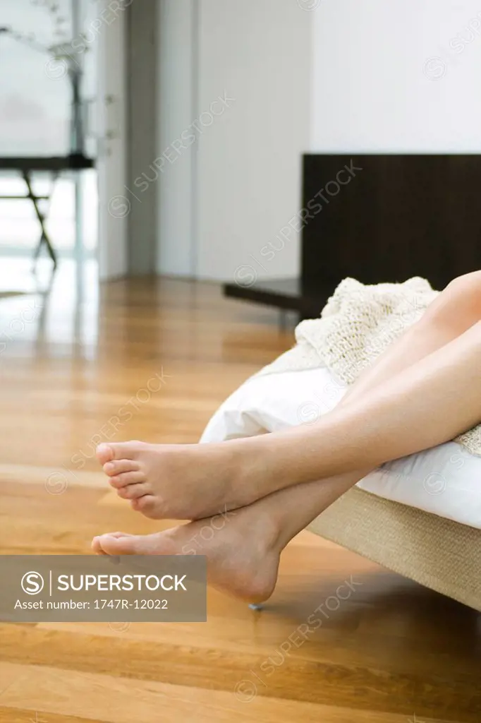 Woman´s bare feet and legs dangling off end of bed