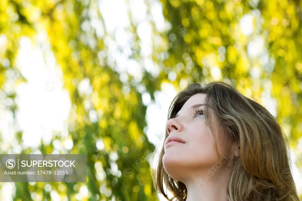 Young woman outdoors, looking up, portrait
