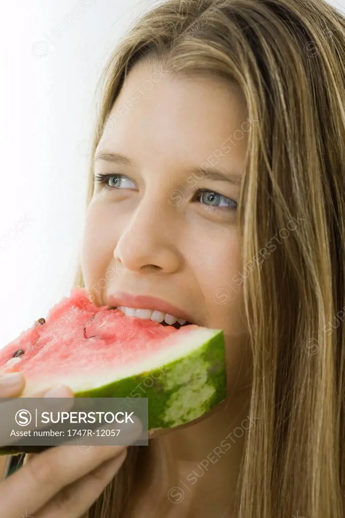 Young woman eating slice of watermelon