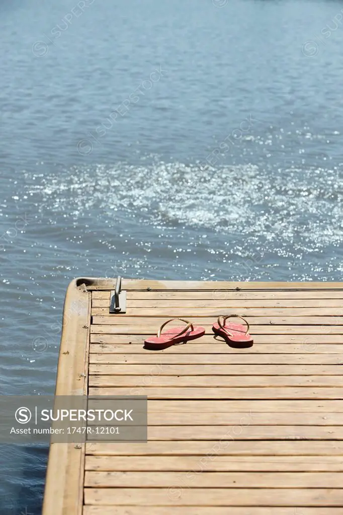 Flip_flops left on dock beside lake