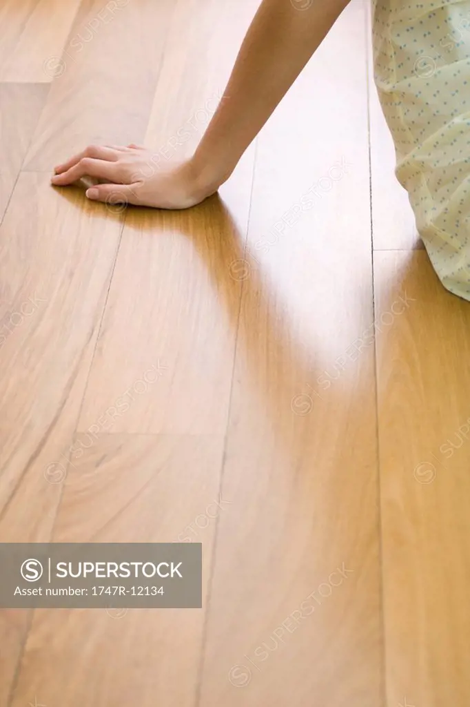 Woman sitting on hardwood floor, cropped