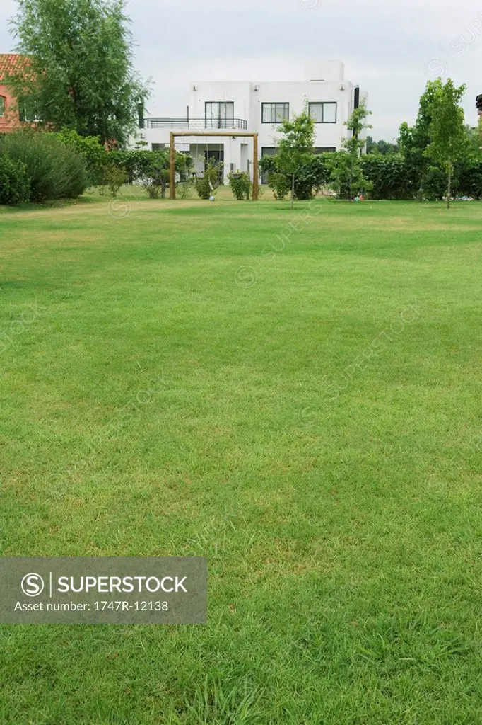 Green lawn, swing set and home in distance