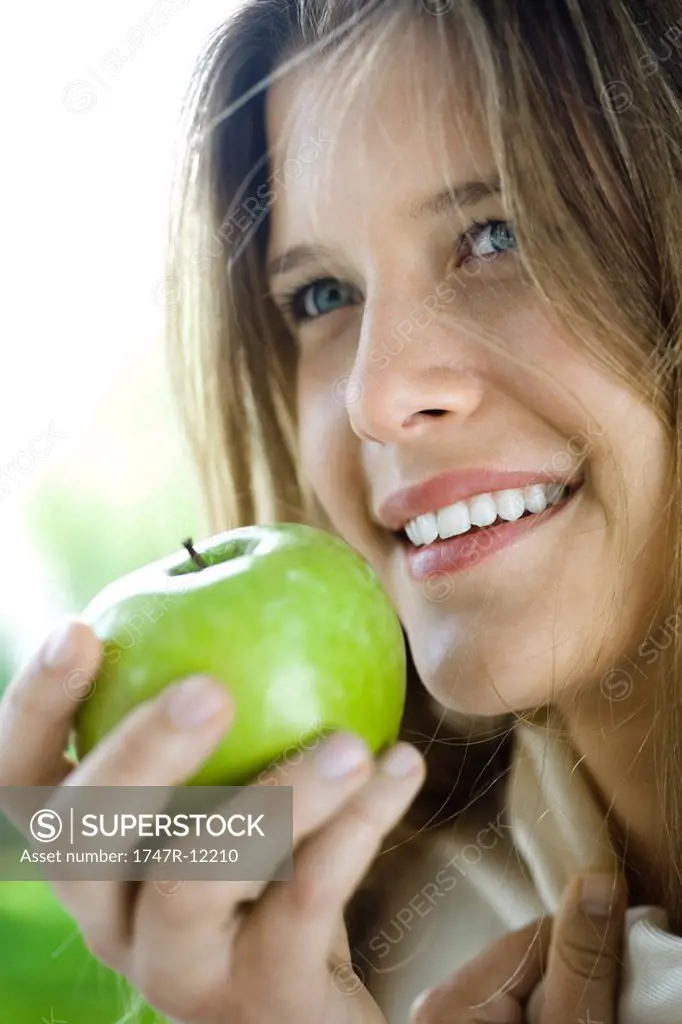 Young woman eating green apple