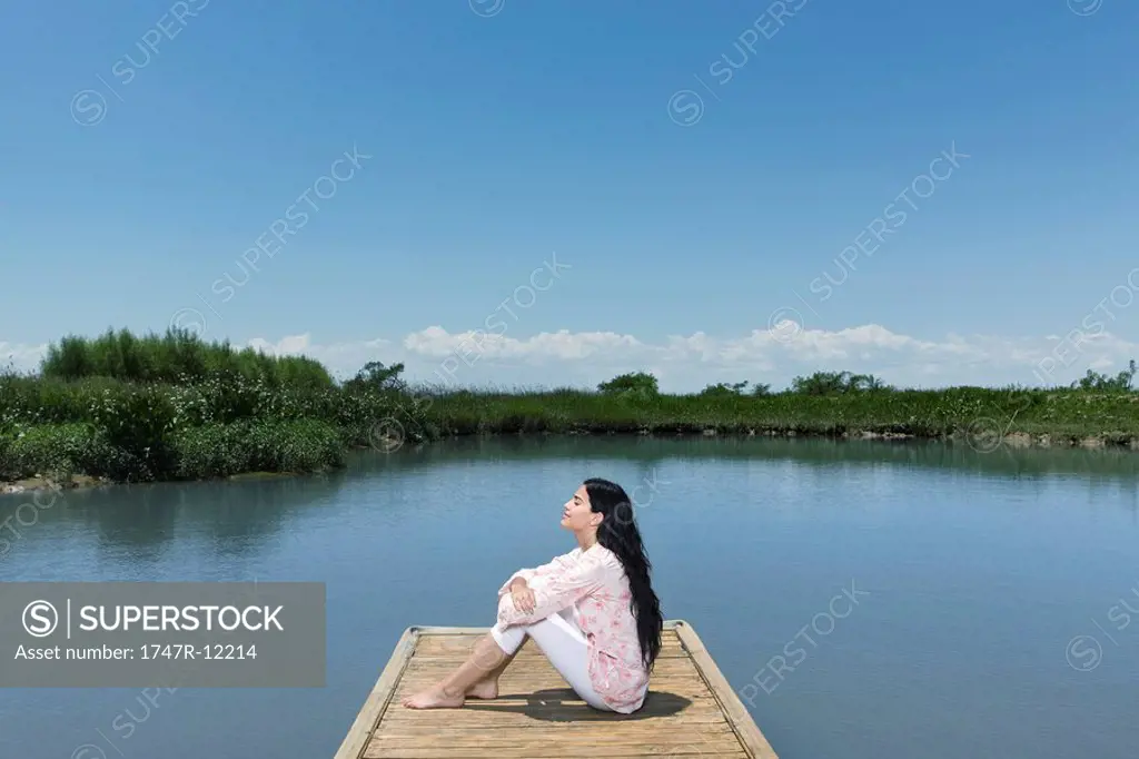 Woman relaxing on dock with eyes closed