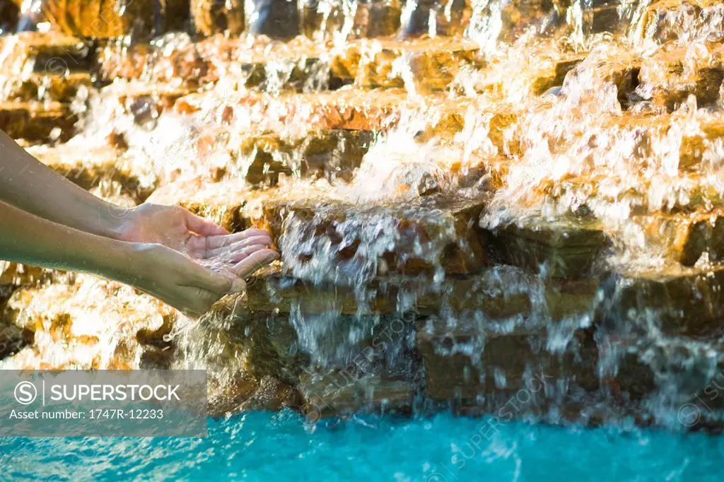Catching water flowing over rocks with cupped hands