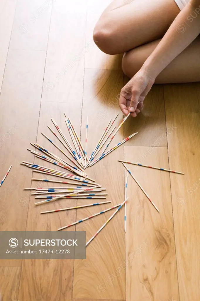 Female playing with pick up sticks on floor