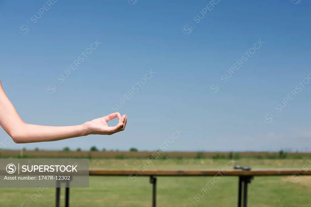 Person meditating outdoors, cropped view of arm in mudra position