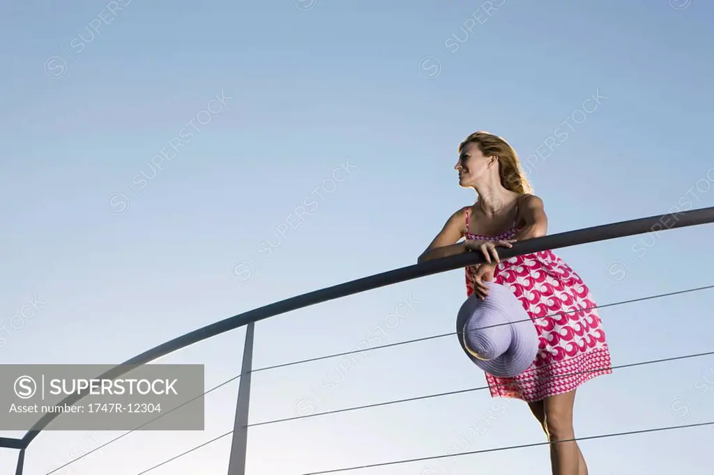 Woman leaning against balcony railing, looking at view