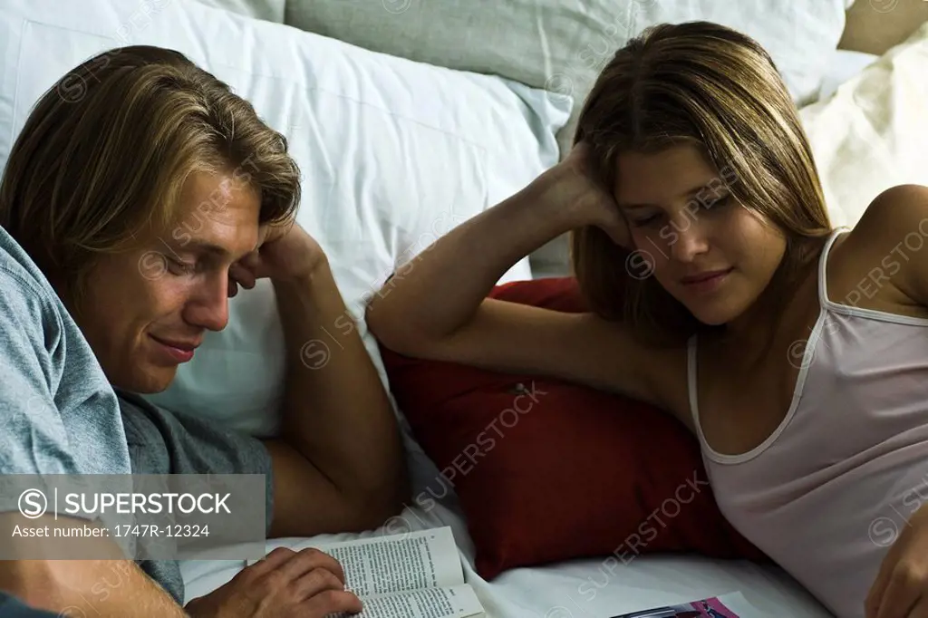Couple reclining together in bed reading