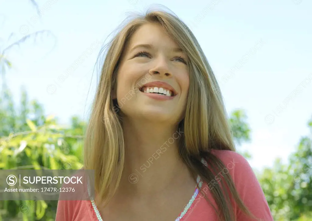 Young woman outdoors, smiling and looking up